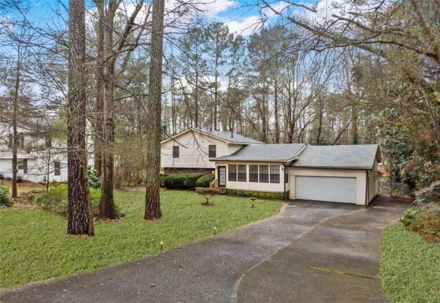 split level home featuring driveway, an attached garage, and a front yard