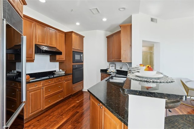 2828 Peachtree Rd NW Unit 1502, Atlanta, GA 30305 - kitchen featuring black appliances, under cabinet range hood, dark wood-style flooring, a peninsula, and recessed lighting