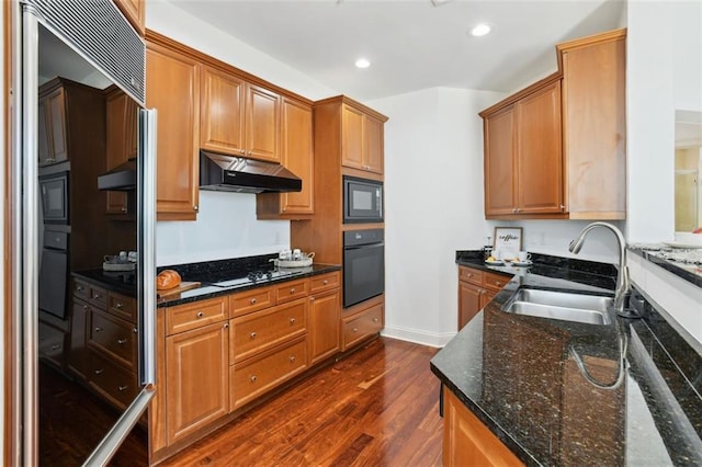 2828 Peachtree Rd NW Unit 1502, Atlanta, GA 30305 - kitchen with black appliances, under cabinet range hood, dark wood-style flooring, dark stone countertops, and recessed lighting