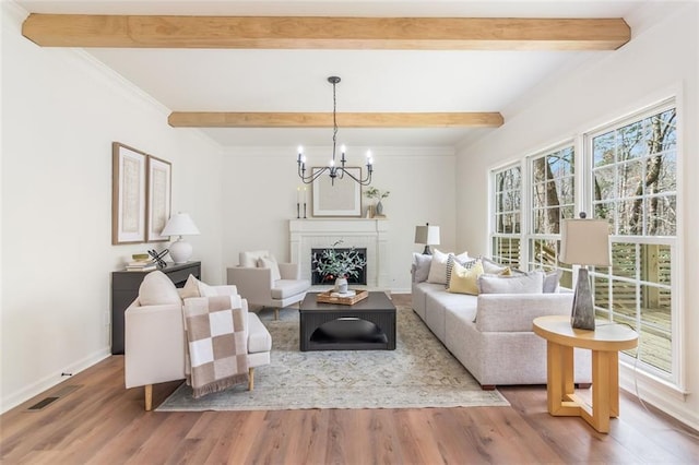 living area featuring visible vents, beamed ceiling, and wood finished floors