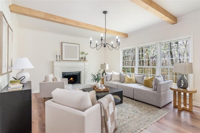 living room with a chandelier, beam ceiling, a fireplace, and wood finished floors