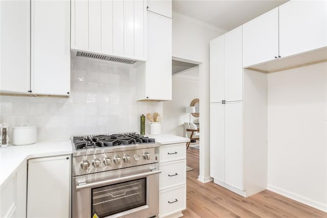 kitchen featuring white cabinets, light wood-style floors, light countertops, backsplash, and high end range