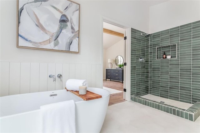 bathroom featuring a soaking tub, tiled shower, and wainscoting