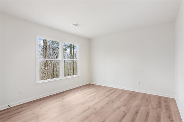 empty room featuring light wood-type flooring, visible vents, and baseboards