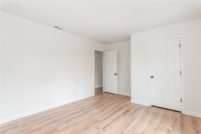 unfurnished bedroom with light wood-style flooring, visible vents, and baseboards