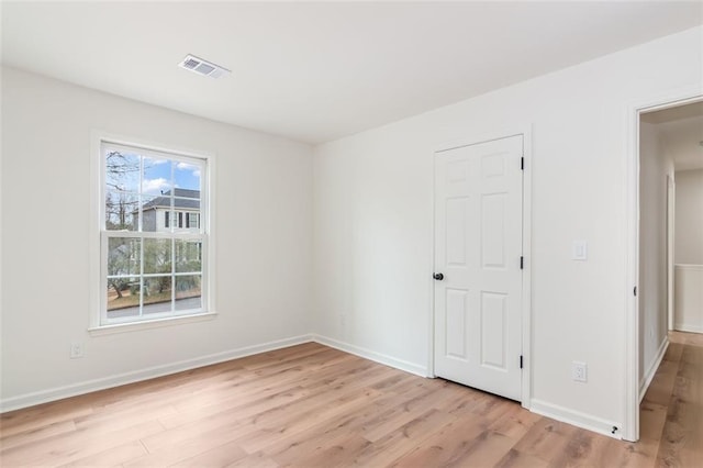 empty room featuring light wood-type flooring, visible vents, and baseboards