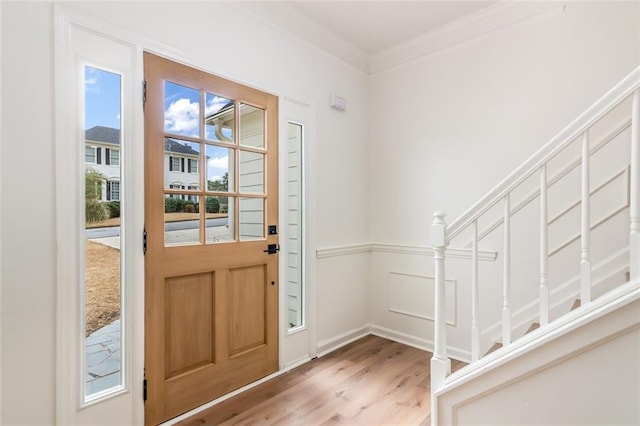 entrance foyer featuring wainscoting, stairway, ornamental molding, wood finished floors, and a decorative wall