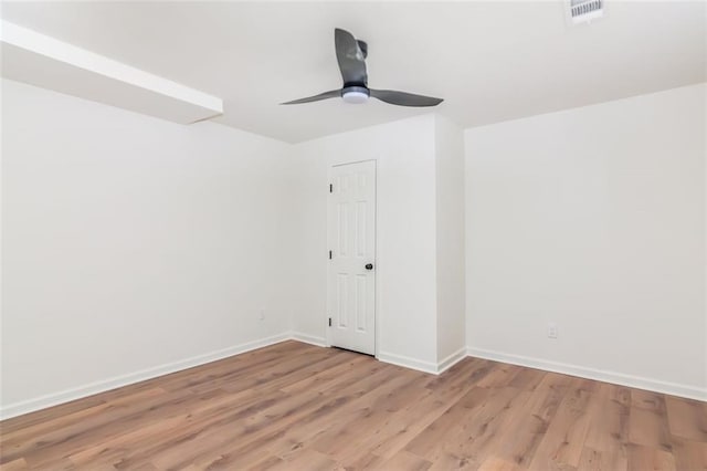 spare room with baseboards, a ceiling fan, visible vents, and light wood-style floors