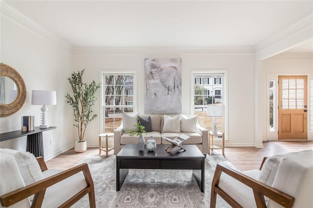 living room with crown molding, light wood-style flooring, and baseboards