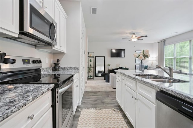 kitchen featuring stainless steel appliances, a sink, white cabinetry, wood finished floors, and ceiling fan