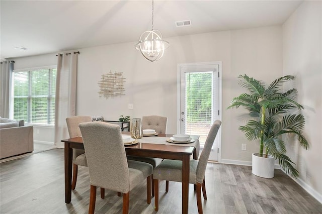 dining room with light wood finished floors, a chandelier, and baseboards