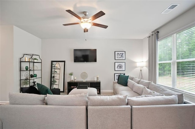 living area featuring a ceiling fan, baseboards, and carpet flooring