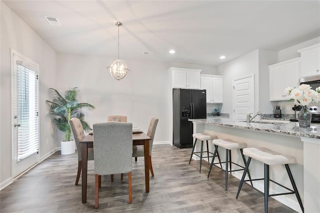 dining area with a chandelier, wood finished floors, baseboards, and recessed lighting