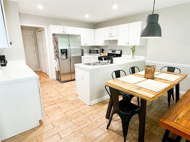 320 Kentshire, Lawrenceville, GA 30044 - kitchen featuring white cabinetry, hanging light fixtures, stainless steel appliances, light hardwood / wood-style floors, and kitchen peninsula