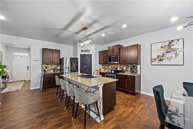 468 Lake Ridge Ln, Fairburn, GA 30213 - kitchen featuring stainless steel appliances, a sink, a breakfast bar area, tasteful backsplash, and dark brown cabinets