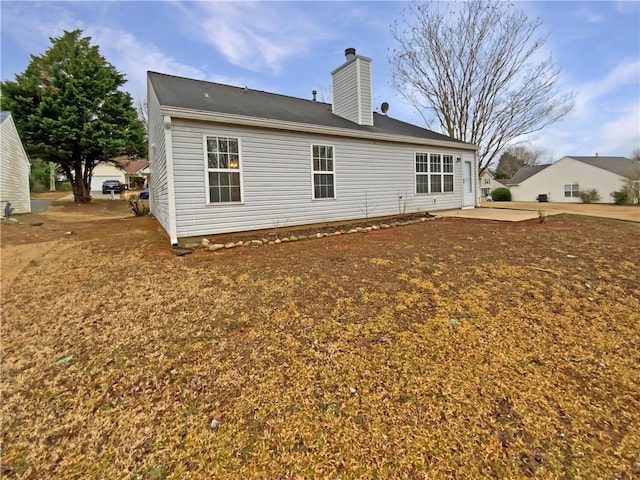 rear view of property featuring a chimney and a patio