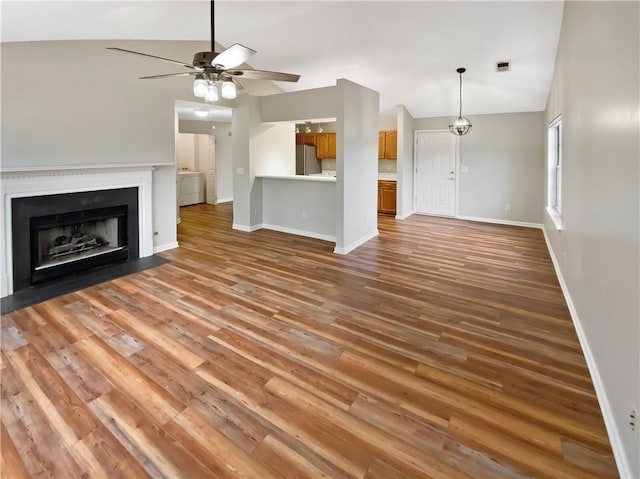 unfurnished living room with a fireplace with flush hearth, light wood-style flooring, baseboards, and ceiling fan