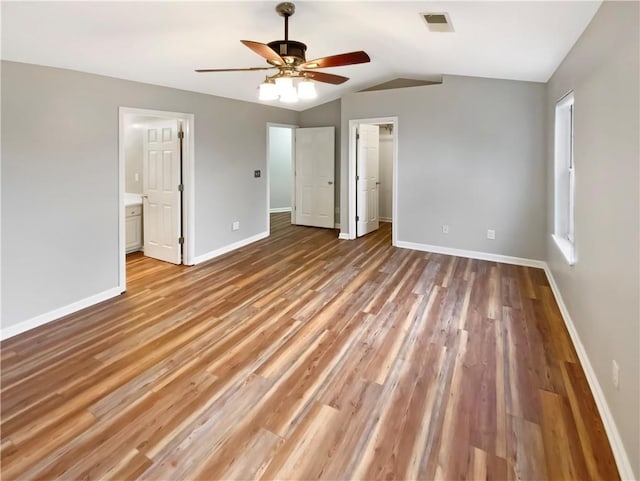 unfurnished bedroom featuring visible vents, lofted ceiling, light wood-style floors, baseboards, and a spacious closet