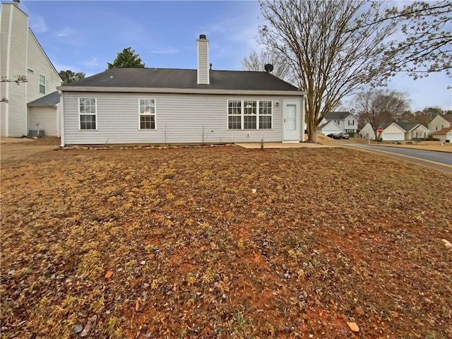 rear view of house with a patio, central AC unit, and a chimney