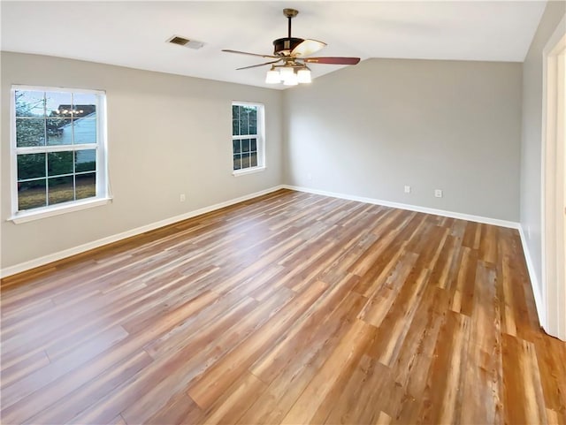 empty room featuring visible vents, plenty of natural light, baseboards, and wood finished floors