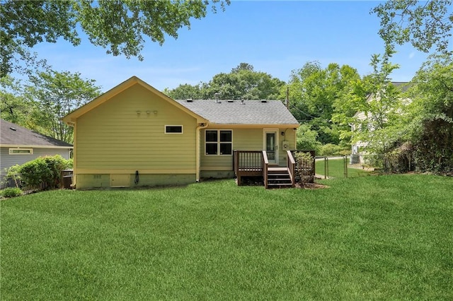 back of property with a deck, fence, and a lawn
