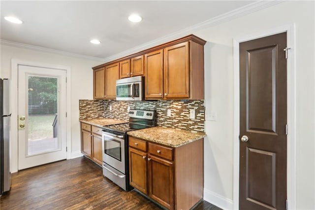 kitchen featuring brown cabinetry, crown molding, dark wood finished floors, backsplash, and stainless steel appliances