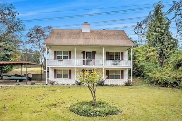 rear view of house with a detached carport, a porch, a yard, a shingled roof, and a chimney