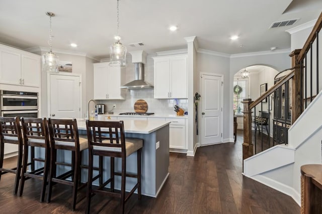 243 Retreat Ln, Canton, GA 30114 - kitchen with wall chimney range hood, arched walkways, double oven, light countertops, and a breakfast bar