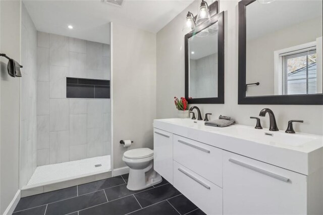 bathroom featuring tile patterned floors, vanity, toilet, and tiled shower