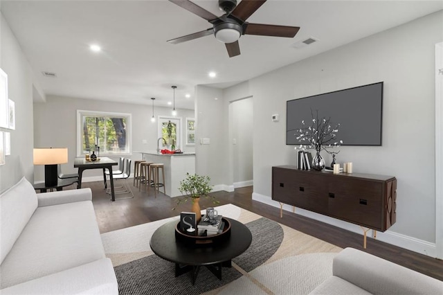 living room featuring ceiling fan and dark hardwood / wood-style floors