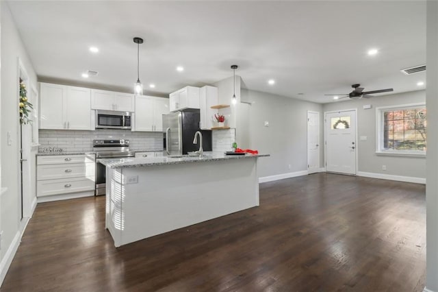 kitchen with hanging light fixtures, dark hardwood / wood-style floors, appliances with stainless steel finishes, light stone counters, and white cabinetry