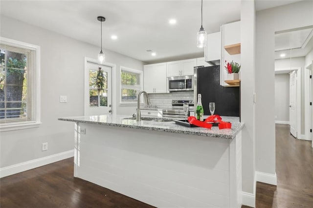 kitchen featuring light stone countertops, appliances with stainless steel finishes, dark wood-type flooring, pendant lighting, and white cabinetry