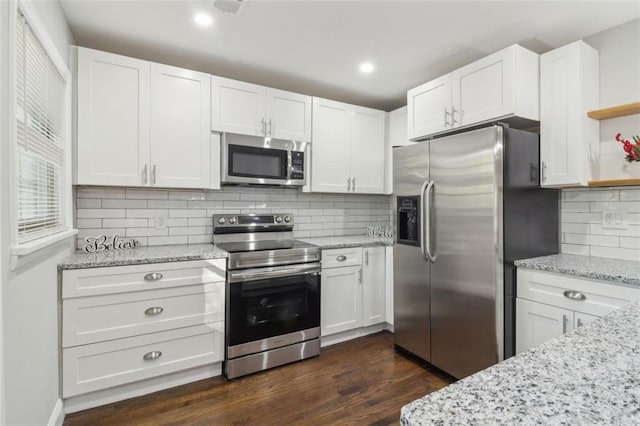 kitchen featuring white cabinets, appliances with stainless steel finishes, decorative backsplash, and dark wood-type flooring