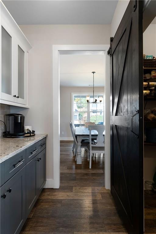 kitchen with white cabinetry, a barn door, hanging light fixtures, dark wood-type flooring, and gray cabinets