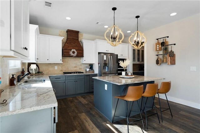 kitchen with premium range hood, dark wood-type flooring, white cabinets, stainless steel fridge with ice dispenser, and a center island