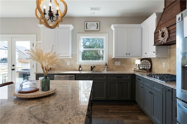 kitchen featuring appliances with stainless steel finishes, sink, dark hardwood / wood-style floors, white cabinetry, and hanging light fixtures