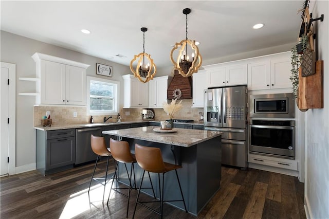 kitchen with white cabinets, a kitchen island, a breakfast bar, dark wood-type flooring, and stainless steel appliances