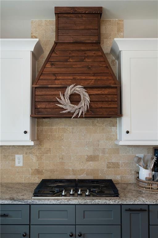 kitchen featuring gray cabinetry, white cabinetry, stainless steel gas stovetop, backsplash, and light stone countertops