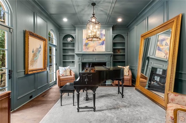 miscellaneous room with built in shelves, crown molding, a notable chandelier, and wood-type flooring