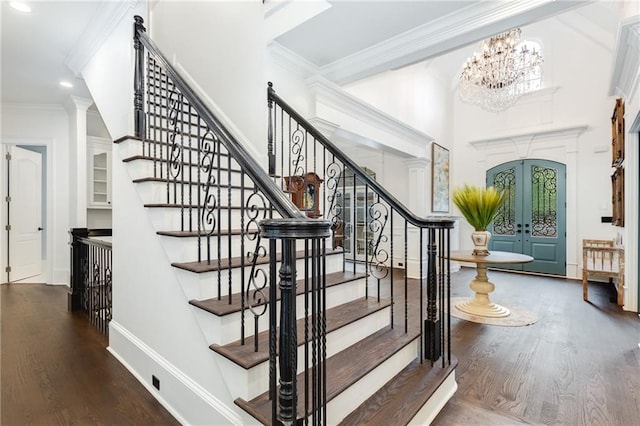 foyer entrance with french doors, crown molding, a notable chandelier, and dark hardwood / wood-style flooring