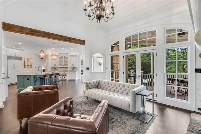 living room featuring high vaulted ceiling, dark hardwood / wood-style floors, a notable chandelier, french doors, and sink