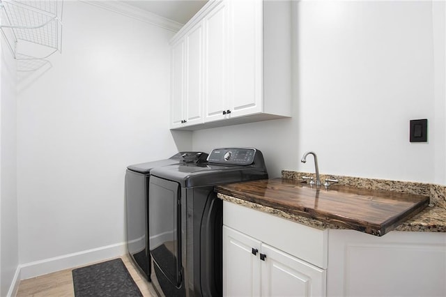 washroom featuring cabinets, independent washer and dryer, light hardwood / wood-style flooring, and crown molding