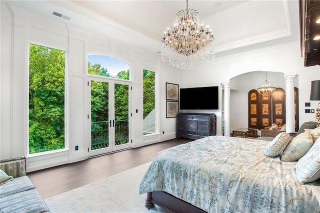 bedroom featuring hardwood / wood-style floors, ornate columns, multiple windows, and access to exterior