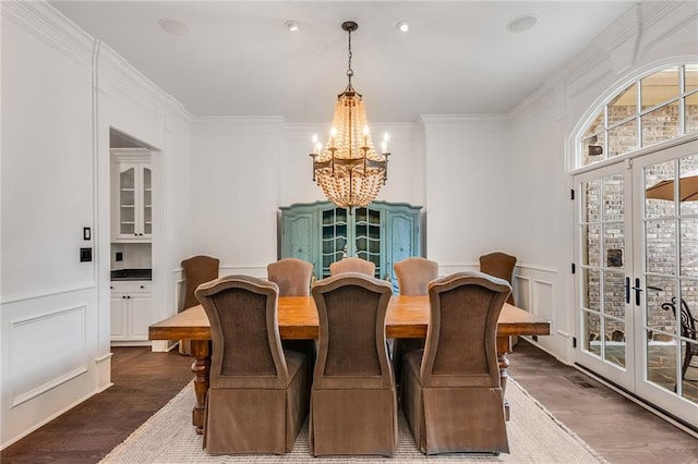 dining space with french doors, crown molding, a notable chandelier, and dark hardwood / wood-style flooring