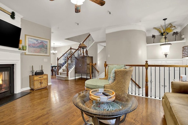 living room with ceiling fan with notable chandelier and dark hardwood / wood-style flooring