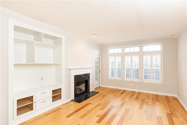 unfurnished living room with a textured ceiling, ornamental molding, a fireplace, and light wood-style flooring