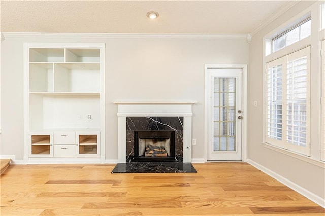 unfurnished living room featuring baseboards, ornamental molding, wood finished floors, and a high end fireplace