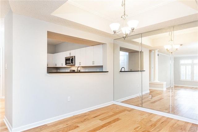 interior space with light wood finished floors, a tray ceiling, and a notable chandelier