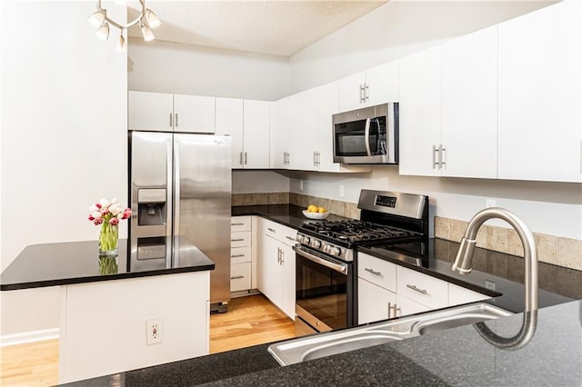 kitchen with appliances with stainless steel finishes, a center island, light wood-style floors, white cabinetry, and a sink