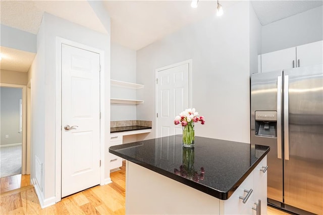 kitchen with light wood-type flooring, white cabinetry, open shelves, and stainless steel fridge with ice dispenser